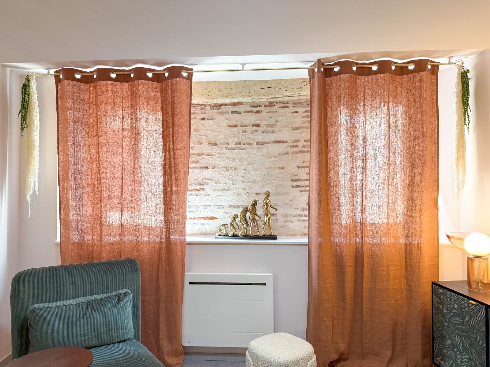 Le salon du cabinet à Castres : fauteuils sauge, rideaux terracotta et arche en pierre